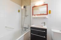 La salle de bains est pourvue d&#39;un lavabo, d&#39;un miroir et d&#39;une douche. dans l&#39;établissement Hôtel De La Plage, à Courseulles-sur-Mer