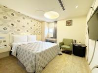 a hotel room with a bed and a green chair at Ai Lai Fashion Hotel in Taichung