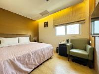 a hotel room with a bed and a chair at Ai Lai Fashion Hotel in Taichung
