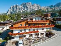 Un edificio con flores en el techo frente a las montañas. en Barisetti Sport Hotel, en Cortina dʼAmpezzo