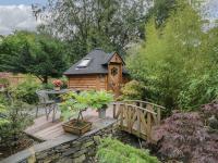 a small wooden house with a table and a bridge at Woodmans Huts in Haverthwaite