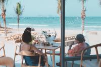 Un grupo de personas sentadas en una mesa en la playa. en iSea by the sea, en Bahía Ninh Van