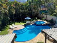 a swimming pool in a yard with chairs and an umbrella at Pousada Estrela do Mar in Maresias