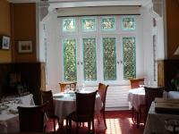 a dining room with tables and chairs and a window at La Villa Bois Joli HOTEL RESTAURANT in Bagnoles de l'Orne