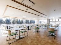 a dining room with tables and chairs and windows at Tabist Kitami Athlete Stays in Kitami