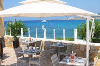 a patio with tables and chairs under an umbrella at Hotel L&#39;ondine in Algajola