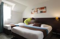 a person in a hotel room with two beds at The Originals City, Hôtel Acadine, Le Neubourg (Inter-Hotel) in Le Neubourg
