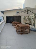 un patio con mesas de madera y una sombrilla en Mayilveedu Guest House, en Thoothukudi