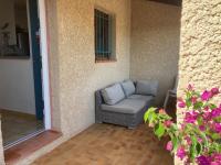 a couch sitting in the corner of a patio at small house 6p in bormes, quiet , hill-view in Bormes-les-Mimosas
