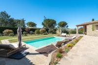 a swimming pool with lounge chairs and an umbrella at La Bastide Des As in Gordes