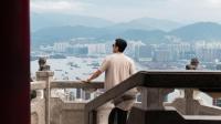 a man standing on a ledge looking out over a city at Four Seasons Hotel Hong Kong in Hong Kong