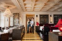 a man and a woman standing in a restaurant at Four Seasons Hotel Hong Kong in Hong Kong