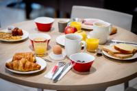 a wooden table with breakfast foods and drinks on it at Ace Hôtel Caen Nord Mémorial in Caen