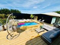 a wooden deck with a swimming pool and a swing at Evasion tropicale in Bretteville-sur-Odon