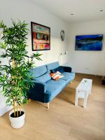 a blue couch in a living room with a plant at Evasion tropicale in Bretteville-sur-Odon
