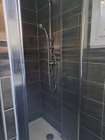 a shower in a bathroom with black tiles at Chambre Solo Duo 20 min Paris - G in Drancy