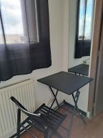 a table and chairs in a room with windows at Chambre Solo Duo 20 min Paris - G in Drancy
