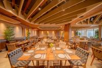 Beach Park Resort - Suites في أكويراز: مطعم به طاولات وكراسي ونوافذ خشبية