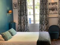 a bedroom with a bed and a window and a chair at Hotel Mirabeau in Tours