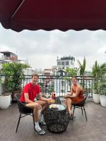 un uomo e una donna seduti su un balcone di Golden Rose Premium Hotel Hanoi a Hanoi
