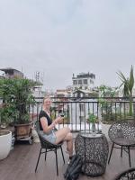 una donna seduta su una sedia su un balcone di Golden Rose Premium Hotel Hanoi a Hanoi