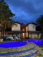 a villa with a swimming pool at night at Pousada Estrela do Mar in Maresias