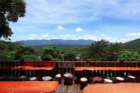 a deck with tables and umbrellas and a view of mountains at JS Hotspring in Ruisui