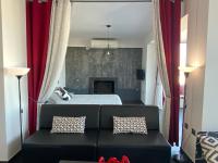 a bedroom with a bed and a couch with red curtains at Luxury view apartment 10min from Athens airport in Koropi