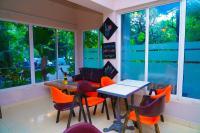 un restaurante con mesa, sillas y ventanas en Tilko City Hotel Jaffna, en Jaffna