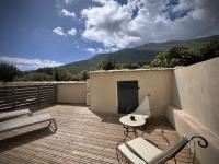 a patio with a table and chairs on a deck at Les 5 Arches in Sisco