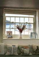 a window with a vase on a shelf with pillows at Kittiwake Cottage - Charming harbour-side cottage, luxury interiors in Port Isaac