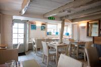 a restaurant with tables and chairs in a room at Kittiwake Cottage - Charming harbour-side cottage, luxury interiors in Port Isaac