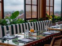 ein langer Tisch in einem Restaurant mit einer gestreiften Couch in der Unterkunft Cross Paasha Bali Seminyak in Seminyak