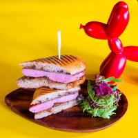 a sandwich on a wooden plate with a red chili pepper at Eastin Grand Hotel Sathorn in Bangkok
