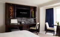a bedroom with a desk with a television on a wall at The Peninsula Chicago in Chicago