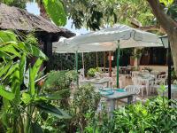 Un patio con mesas y sillas y una sombrilla. en Hostal Mi Campaña, en Denia