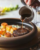 una persona que vierte salsa en un recipiente de comida en Naatooh Guest Houses, en Florianópolis