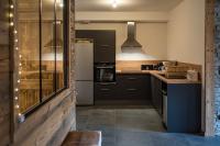 a kitchen with black cabinets and a white refrigerator at Appartement neuf avec une grande terrasse au cœur du village - 6 personnes in Saint-Sorlin-dʼArves