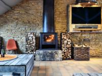 a stone fireplace in a room with a tv and a chair at Fancy Holiday Home in Sainte C cile with Pool House Indoor Pool in Sainte-Cécile