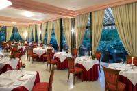 Un restaurante con mesas y sillas blancas y ventanas. en Villa Pace Park Hotel Bolognese, en Preganziol