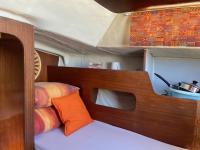 a bedroom with a wooden bed with an orange pillow at Nuit insolite dans un petit voilier in La Rochelle