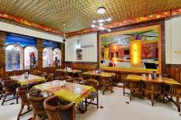 ein Restaurant mit Tischen und Stühlen und einem Gemälde an der Wand in der Unterkunft Hotel President in Gorakhpur