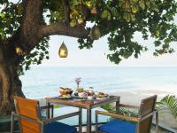 Ein Tisch mit Essen darauf unter einem Baum neben dem Strand in der Unterkunft Explorar Koh Phangan - Adults Only Resort and Spa in Haad Rin