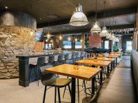 Un restaurante con mesas y sillas de madera y un bar. en Balcomo, a Ramada by Wyndham, en Penticton