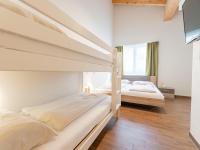 two beds in a bedroom with white walls and wooden floors at Emma Top 3 XL in Dienten am Hochkönig