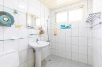 a white tiled bathroom with a sink and a window at Yishin Garden B&amp;B in Pinghe