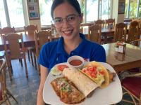 a woman sitting at a table with a plate of food at Badladz Beach and Dive Resort in Puerto Galera