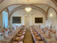 Habitación grande con mesas, sillas y lámpara de araña. en GOYA Vitality Hotel, en Voderady