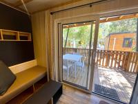 Cette chambre dispose d&#39;une porte coulissante en verre avec une table sur une terrasse. dans l&#39;établissement Camping La Pinède, à Calvi