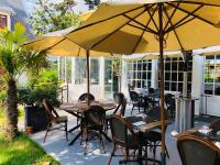 an outdoor patio with tables and chairs and umbrellas at Hôtel-Restaurant La Mascotte in La Baule